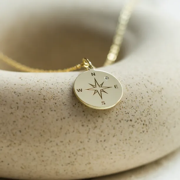 Gold pendant with a compass and a diamond MAP Image