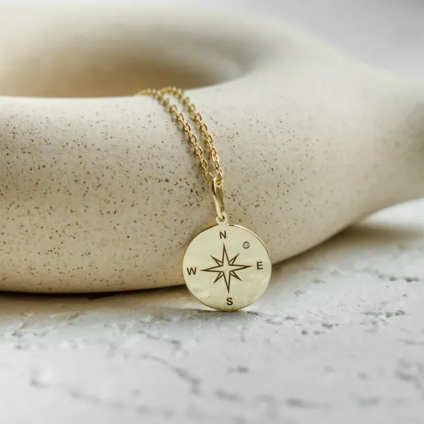Gold pendant with a compass and a diamond MAP Image